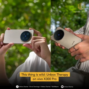 Close-up of two hands holding a gold-colored vivo X300 Pro smartphone with a large, circular camera module on the back, set against a blurred green forest background. The text overlay reads: "This thing is wild: Unbox Therapy on vivo X300 Pro".