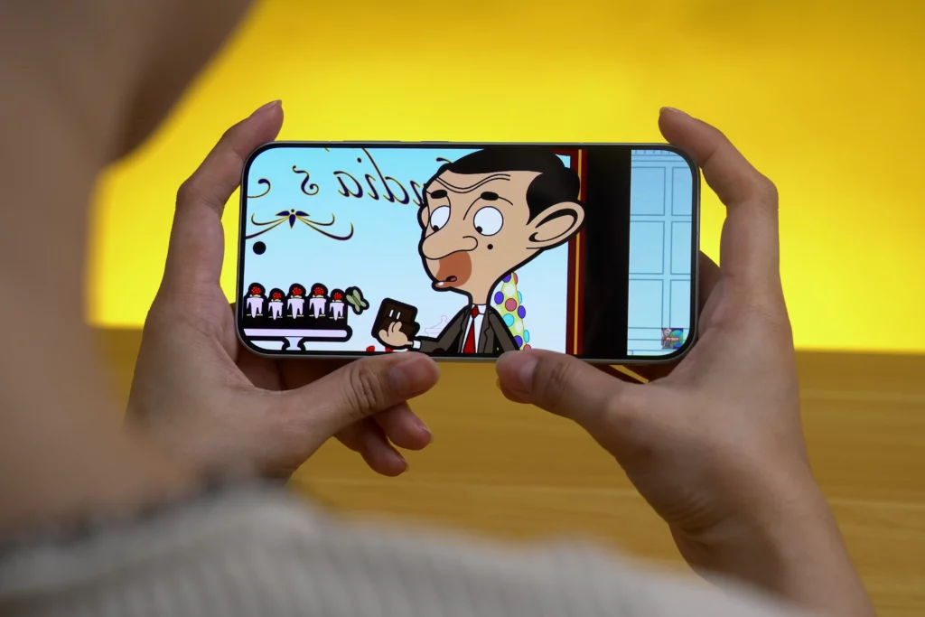 The POCO F8 Pro is held horizontally by hands, displaying a scene from an animated Mr. Bean episode on its screen.