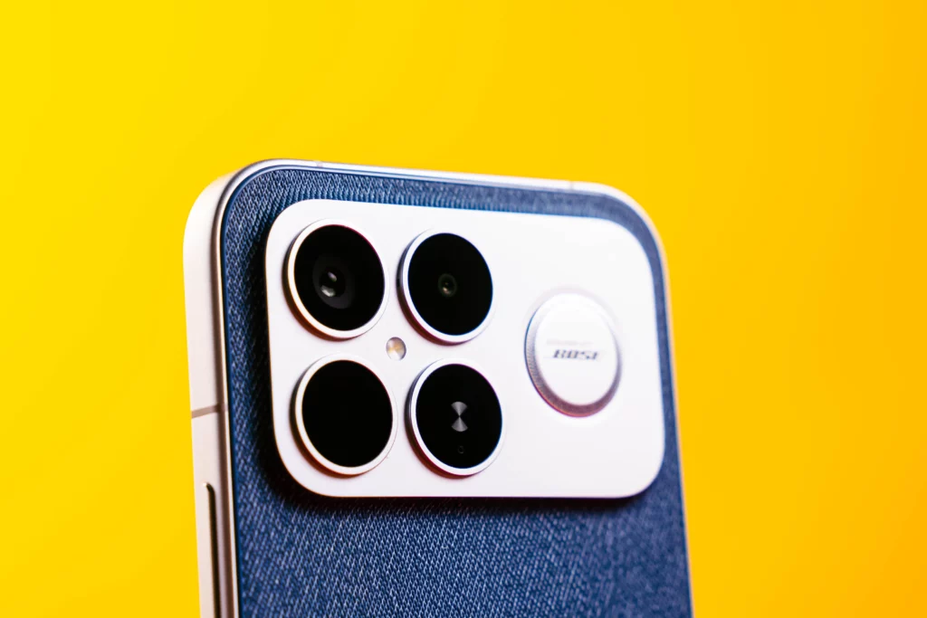 A close-up of the rear camera module on the blue, textured back of the POCO F8 Ultra. The module has four lenses and a metallic accent, possibly indicating a collaboration (e.g., "Bose" logo is faintly visible).