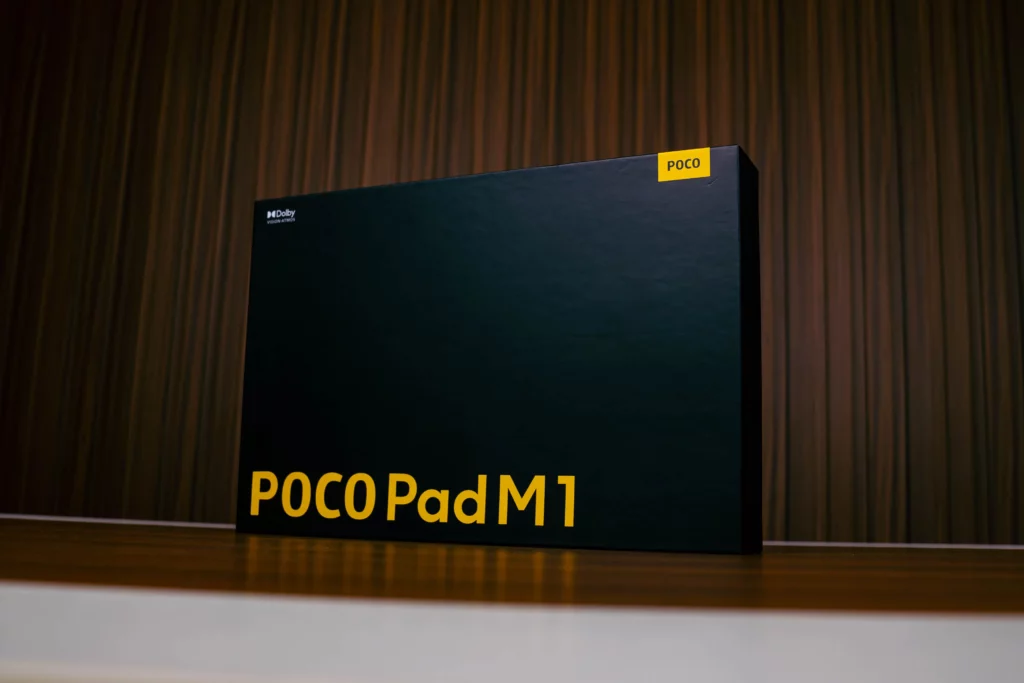 Black retail box for the POCO Pad M1 tablet. The box features the "POCO Pad M1" text in large yellow letters at the bottom, a smaller yellow POCO logo label in the corner, and the Dolby Vision-Atmos logo.