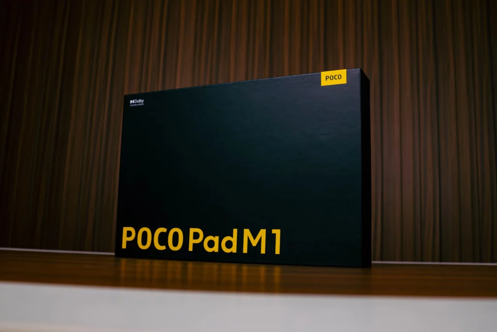 Black retail box for the POCO Pad M1 tablet. The box features the "POCO Pad M1" text in large yellow letters at the bottom, a smaller yellow POCO logo label in the corner, and the Dolby Vision-Atmos logo.