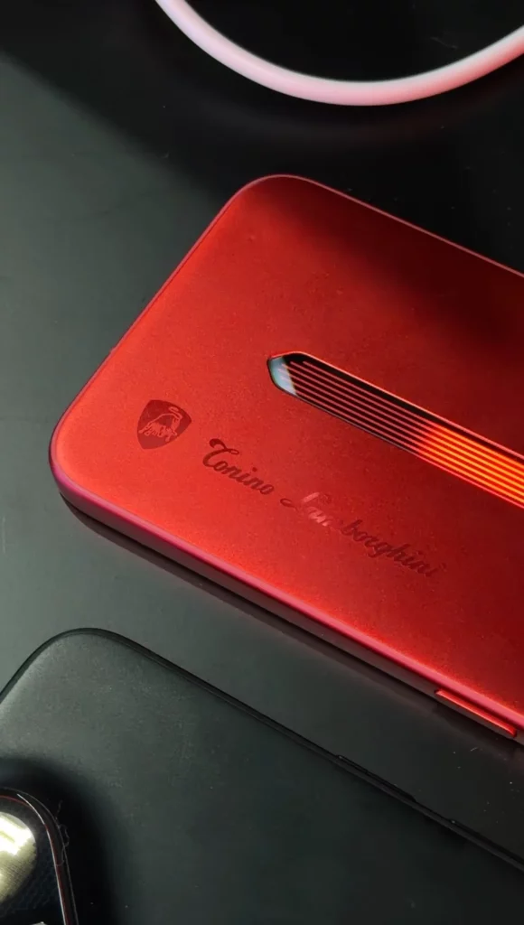 A hand holding the red Tonino Lamborghini edition phone, showcasing its full-metal unibody construction. The "Tonino Lamborghini" branding is printed vertically in large, bold letters along the side of the device.