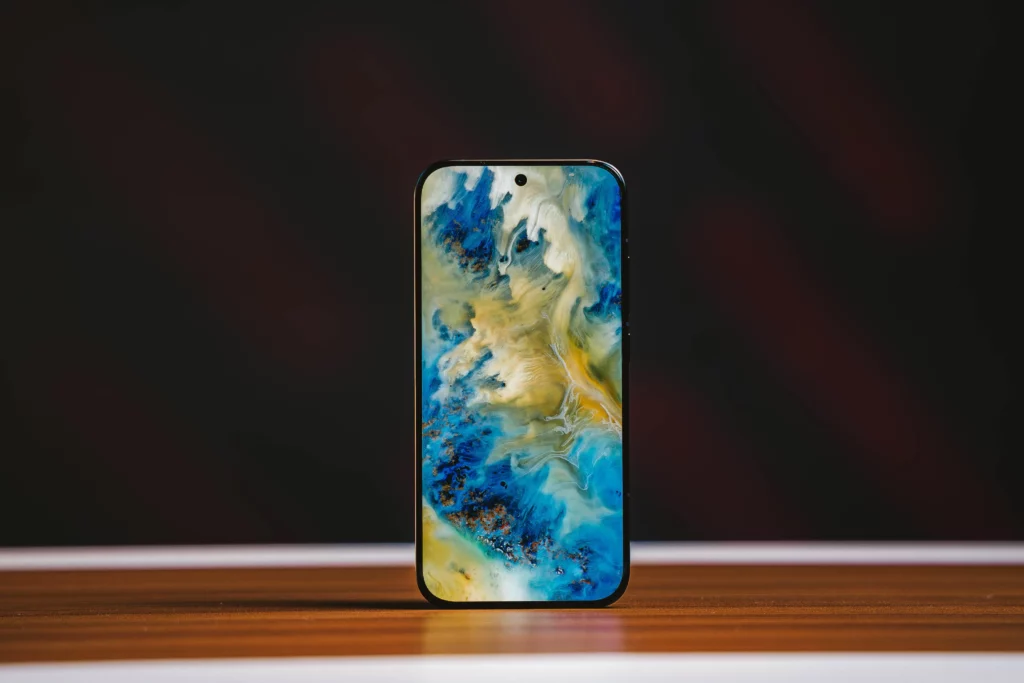 The POCO X8 Pro Iron Man Edition standing atop a wooden surface with the screen showing a yellow and blue abstract image.
