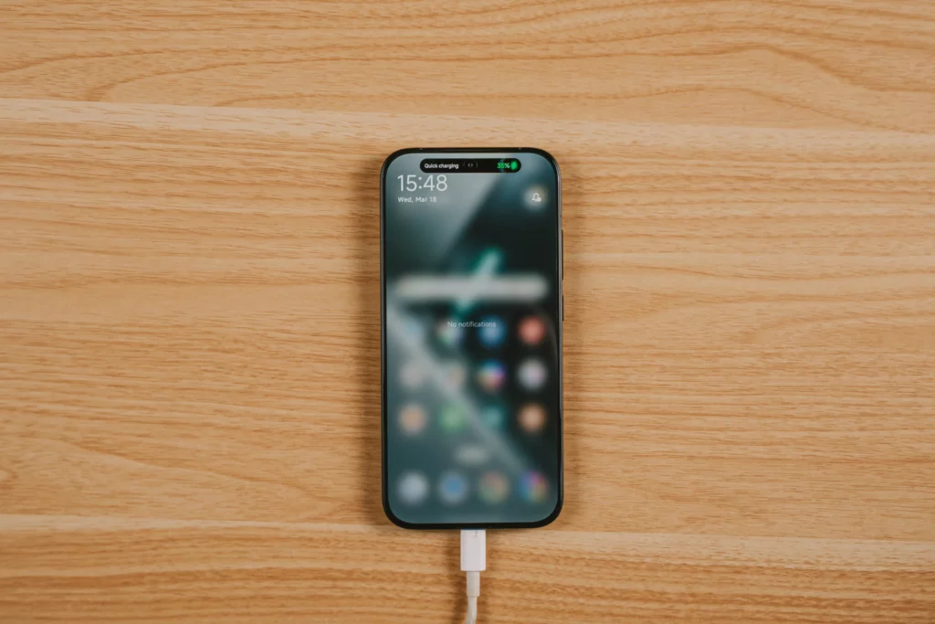 Another shot of the POCO X8 Pro Iron Man Edition plugged in atop a wooden surface with the screen showing Quick charging 35% in the dynamic island.