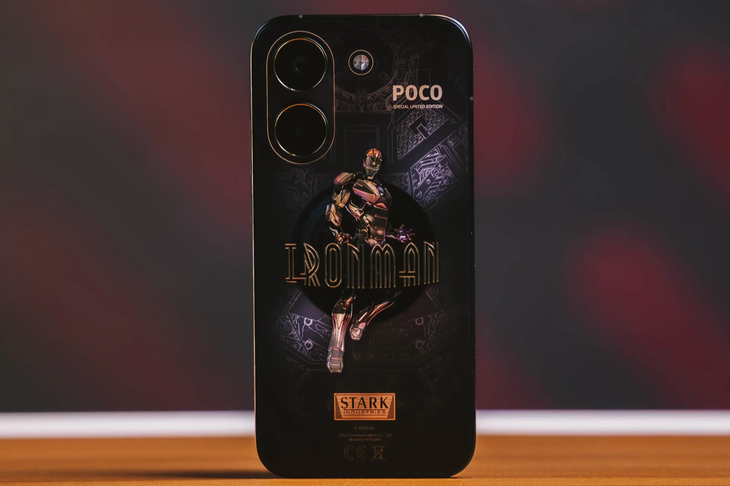 A photo of the POCO X8 Pro Iron Man Edition standing on a wooden table, showcasing the Iron Man design.
