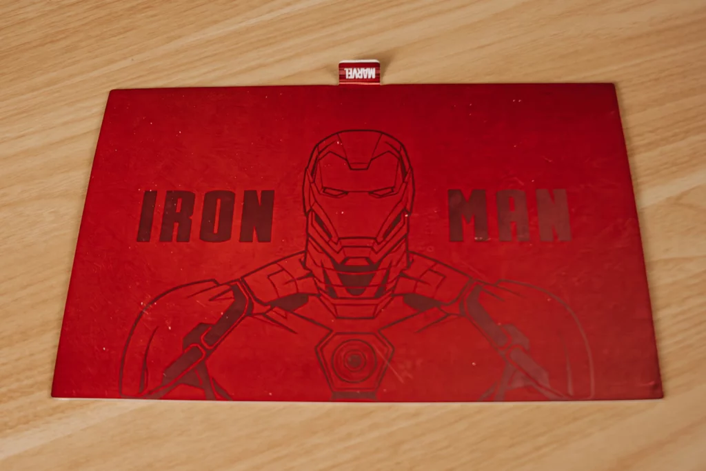 A red art card with an outlined of the Iron Man suit and the words IRON MAN printed.