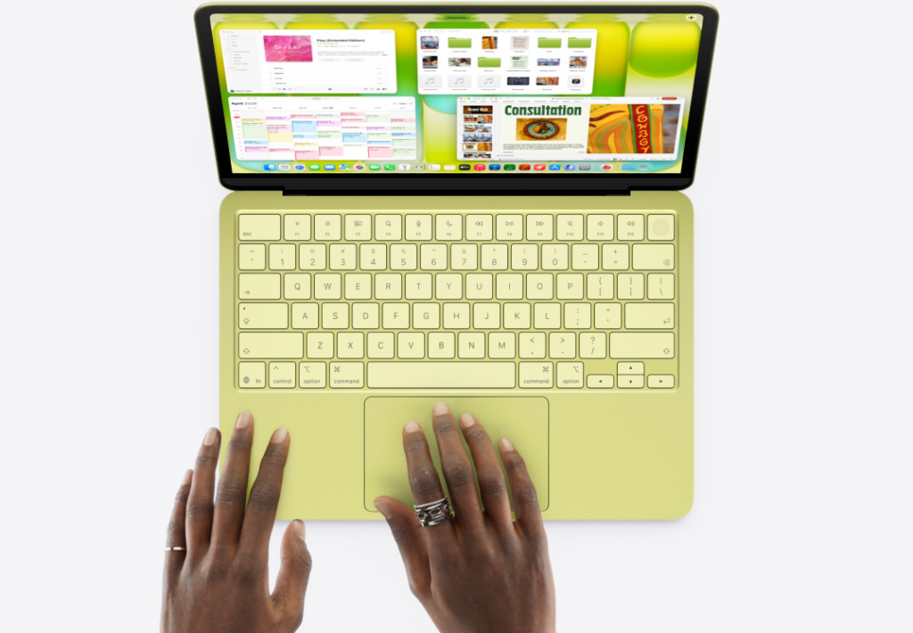 A top-down view of a yellow MacBook Neo being used. Two hands are resting on the matching yellow palm rest and trackpad. The screen shows a macOS desktop with several open windows, including a calendar, music player, and a document titled "Consultation."