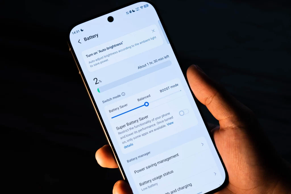 A hand holding the vivo V70 5G displaying the Battery settings menu. The screen shows 2% battery remaining with an estimate of 1 hour and 30 minutes left, highlighting the "Super Battery Saver" mode.
