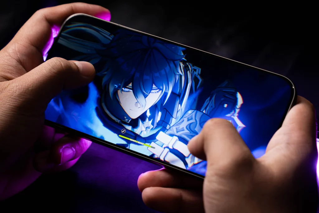 A person holding the vivo V70 5G horizontally, playing a visually intensive game (Genshin Impact). The screen shows an anime-style character with glowing blue effects, emphasizing the phone's gaming capabilities.