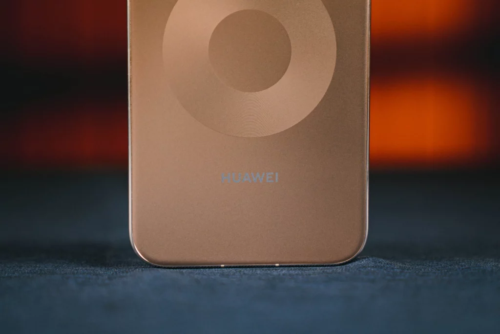 A macro shot of the lower back panel of the device, highlighting the subtle "HUAWEI" branding and the fine, sandblasted texture of the metallic bronze surface.