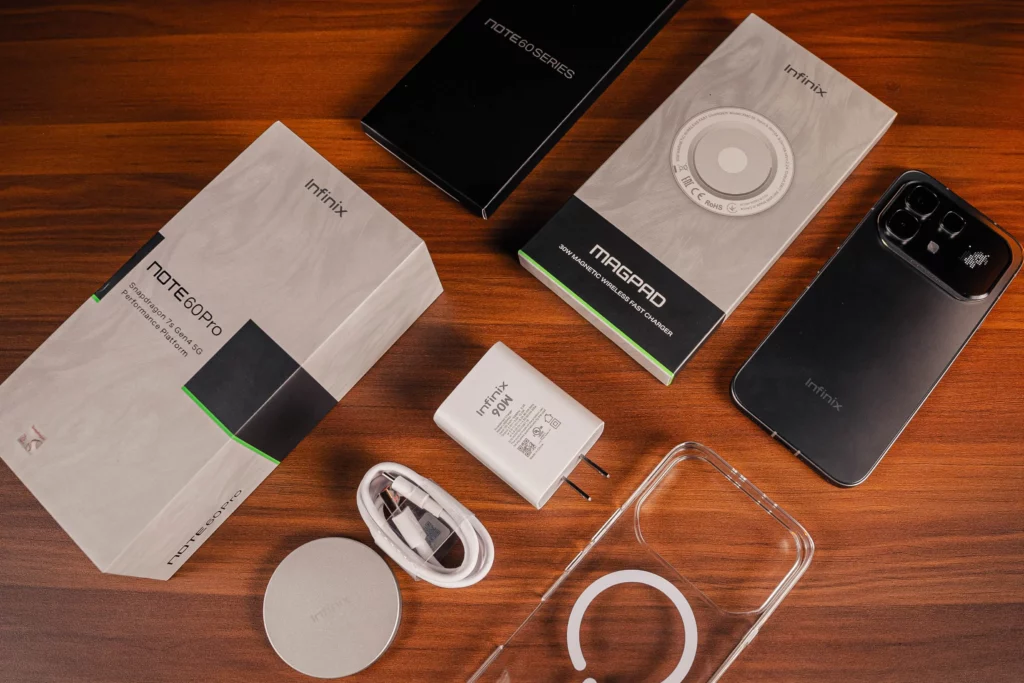 A flat-lay unboxing of the Infinix NOTE 60 Pro, showcasing the device, a clear magnetic case, a 90W fast-charging brick, a USB-C cable, and the 30W MagPad wireless charger.