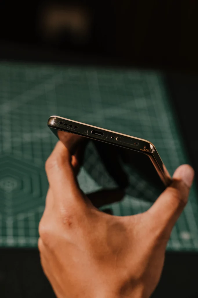 A hand holding the realme 16 Pro+ 5G showing the bottom part with the speaker grille, charging port, and sim tray.