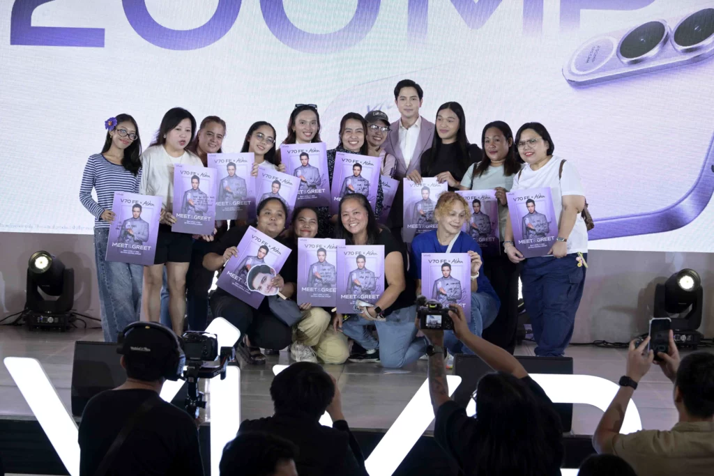 Alden Richards poses for a group photo with fans and pre-order winners at the SM Mall of Asia Atrium. The fans are smiling and holding up signed "Meet & Greet" posters featuring Alden Richards and the vivo V70 FE.