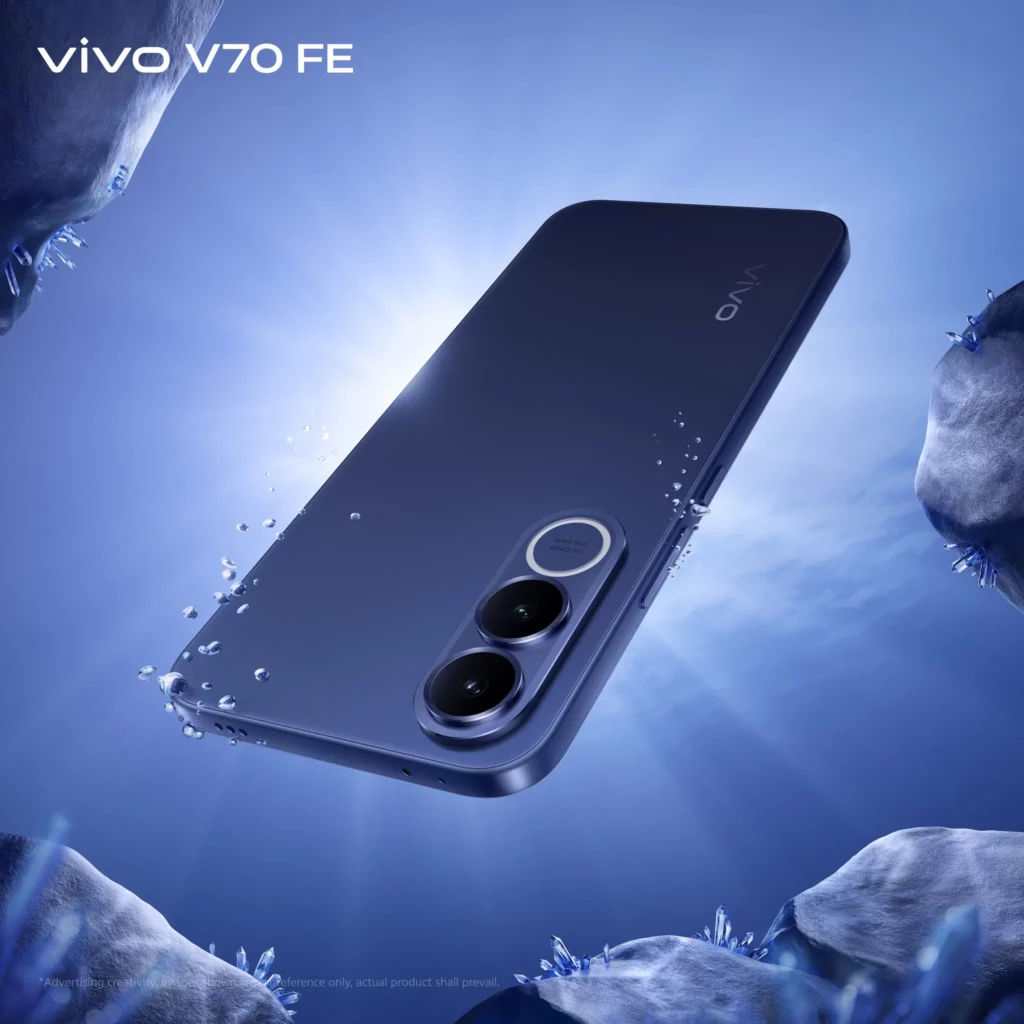 A rear view of the vivo V70 FE in Ocean Blue, shown floating in a deep blue underwater environment. The phone has a dark, matte blue finish. Light rays penetrate from above, illuminating water droplets and crystalline rock formations around the device.
