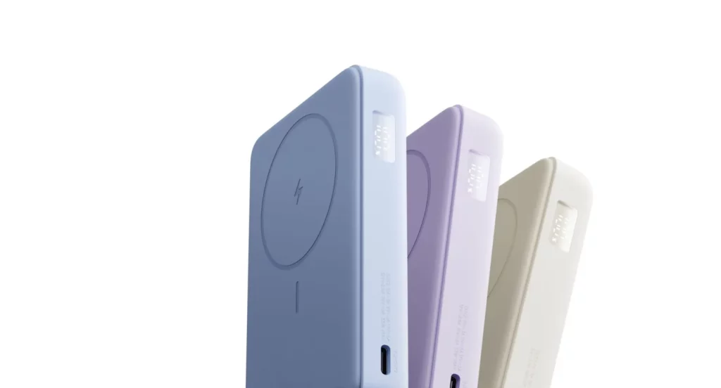 Three Xiaomi magnetic power banks with built-in stands shown in light blue, purple, and cream. The side-view highlights the circular magnetic charging area and a small digital display on the edge showing the battery percentage.