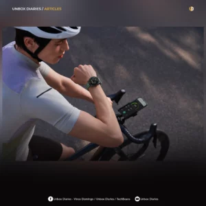 A cyclist wearing a white helmet and cycling jersey checks a round smart watch with a green textured band while riding on an asphalt road. A smartphone displaying a fitness tracking application is mounted onto the bicycle's handlebars.
