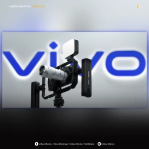 An article feature image with a blurred, dark vignette border, showing a smartphone mounted on a professional video rig and tripod. The rig includes a silver ZEISS external lens, a top-mounted LED light panel, and a "SmallRig x vivo" side handle. A large, illuminated blue and white vivo logo is blurred in the background. The text "UNBOX DIARIES / ARTICLES" is visible at the top left, with social media handles at the bottom.