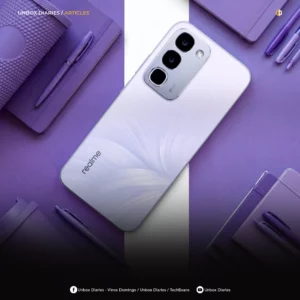 A top-down product photograph featuring a realme smartphone centered diagonally on a split purple and white background. The phone has a light purple back panel accented with a subtle, flowing feather-like pattern and the "realme" logo printed near the bottom. Its vertical, metallic-finished camera module contains three stacked lenses and an LED flash. Surrounding the smartphone are matching monochromatic purple items, including multiple notebooks, pens, and a textured tumbler. Branding for "UNBOX DIARIES / ARTICLES" is visible at the top, with social media handles for Vince Domingo, TechBeans, and Unbox Diaries along the bottom border.