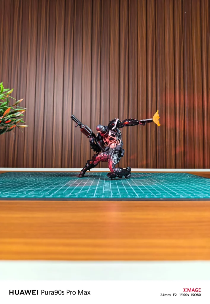 Wide shot of a black and red superhero action figure in a dynamic tactical pose holding weapons on a green cutting mat.