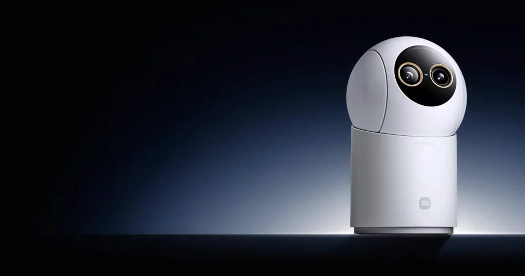 Close-up of the white Xiaomi Smart Camera C701 Pro featuring a prominent dual-lens camera system with gold accents, set against a dark blue gradient background.
