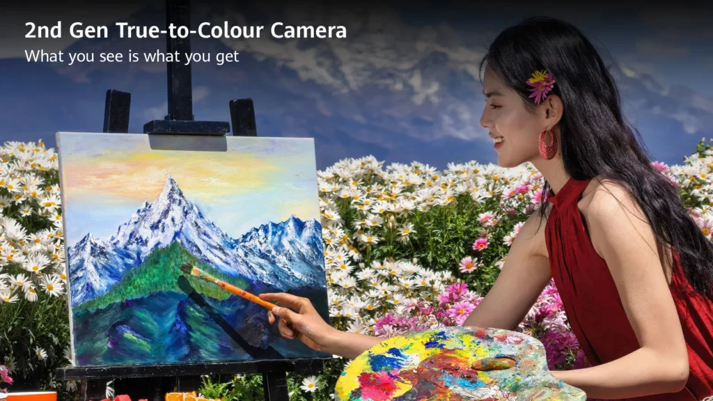 Woman painting a snow-capped mountain landscape on a canvas in a field of flowers, highlighting the 2nd Gen True-to-Colour Camera.