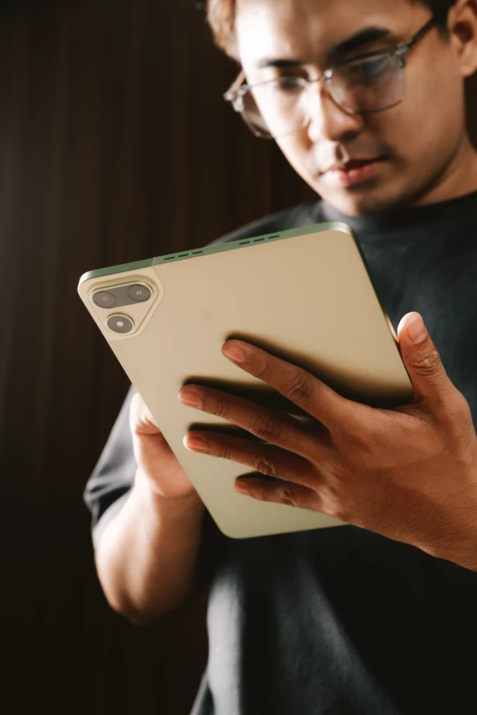 A man wearing glasses holds a light green TECNO MEGAPAD 2 tablet vertically, showing off its back panel design and rear camera module.