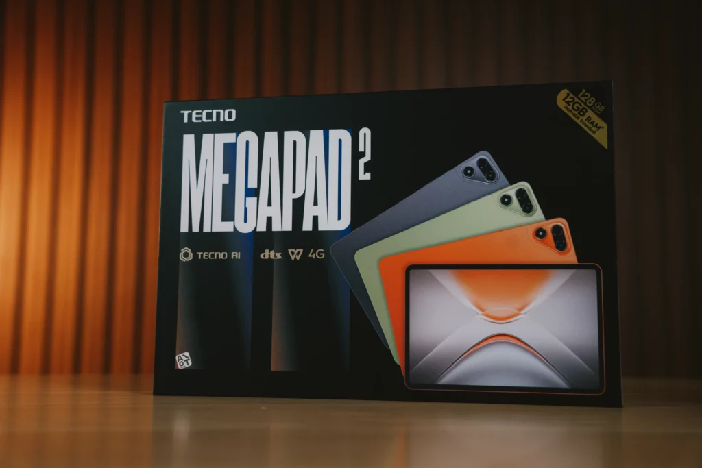 Front view of the black retail packaging box for the TECNO MEGAPAD 2, highlighting product features like 12GB RAM, 128GB ROM, and color options.