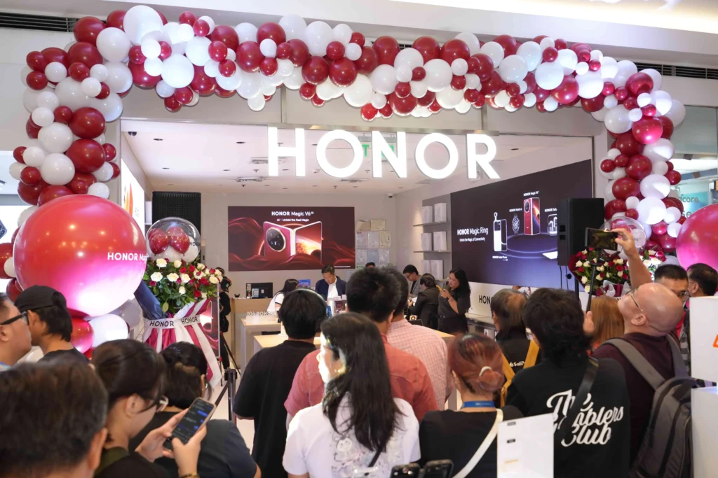 A large crowd gathered outside the HONOR Store entrance, decorated with red and white balloon arches, during the first-day sale event.