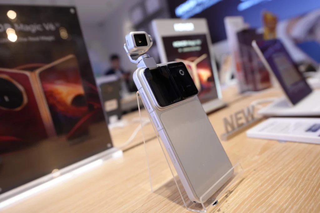 Close-up shot of a white smartphone featuring a motorized, gimbal-style detachable camera module mounted on top, displayed on a wooden stand.