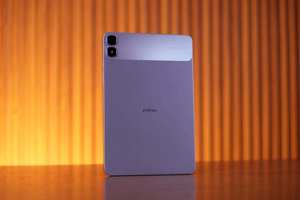 Rear view of the light purple Infinix XPAD 30 Pro tablet standing vertically on a wooden table, featuring a dual rear camera module at the top corner and a central Infinix logo.