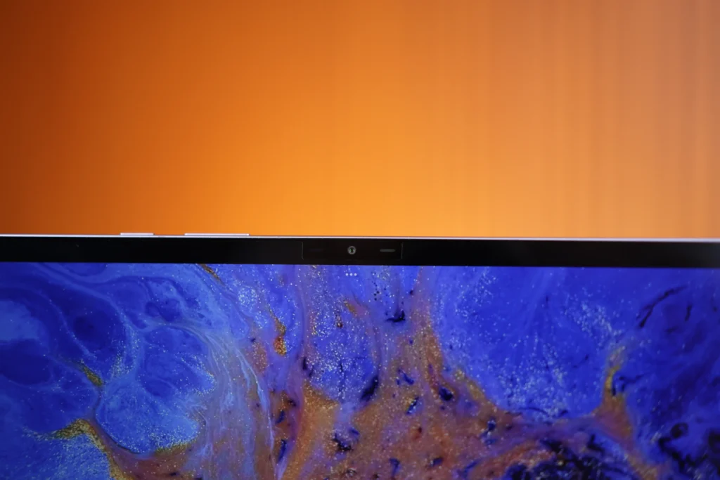 Close-up view of the top screen bezel of the Infinix XPAD 30 Pro tablet, showing the front-facing camera lens set against a blue and gold fluid wallpaper.
