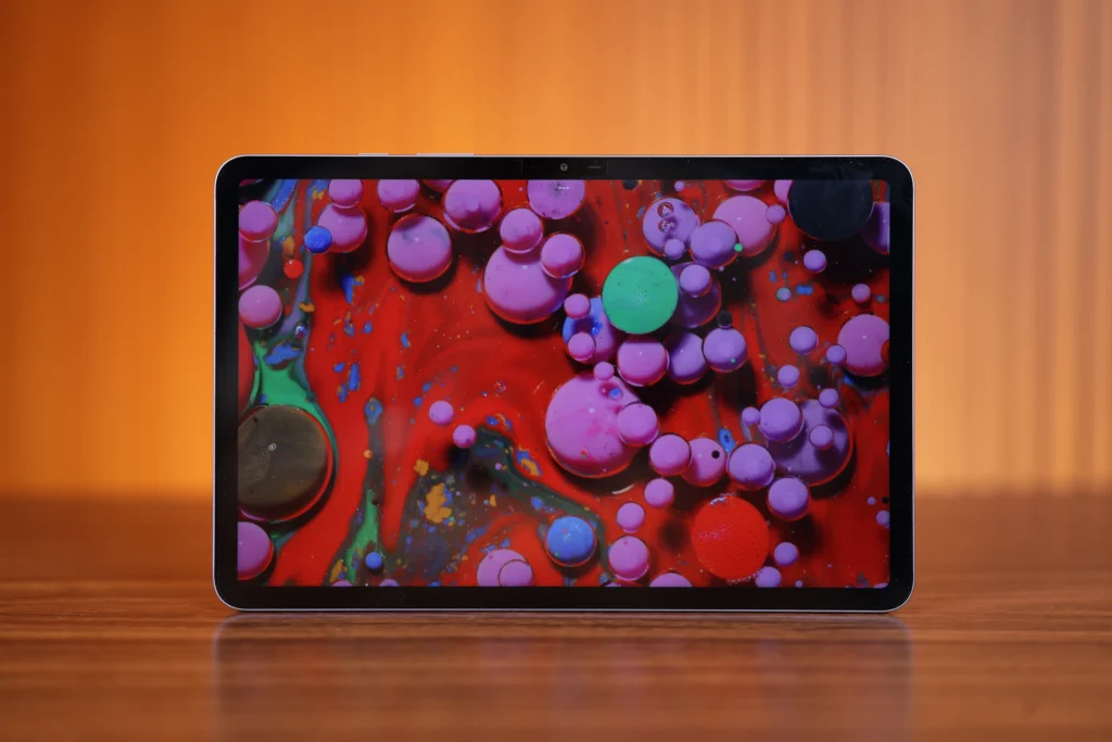 Front view of the horizontally positioned Infinix XPAD 30 Pro tablet, displaying a vivid background image filled with colorful liquid bubble textures in shades of purple, green, and red.