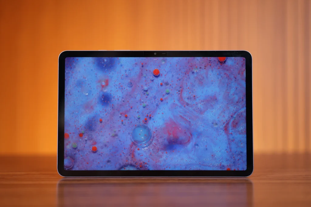 Front view of the Infinix XPAD 30 Pro tablet in landscape orientation, featuring a textured light blue wallpaper with small red dots on the screen.