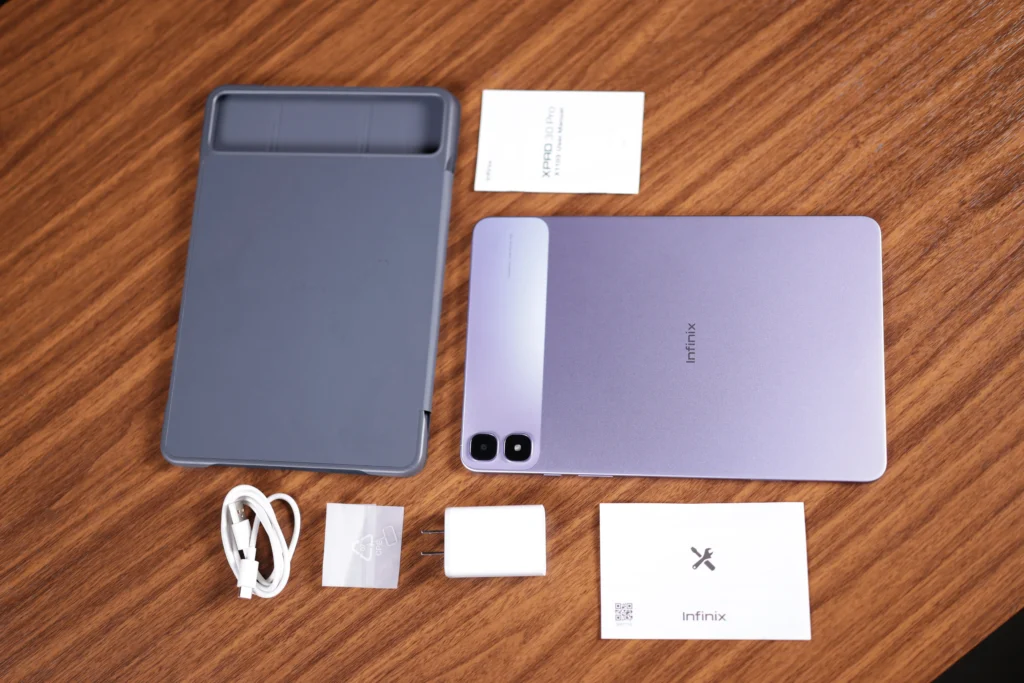 Top-down flat lay view of the unboxed Infinix XPAD 30 Pro tablet surrounded by included accessories: a grey protective case, USB-C cable, charging brick, user manuals, and SIM ejector tool.