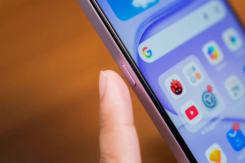 A close-up view of a finger near the side power button and the front screen of the purple HONOR 600S 5G smartphone.