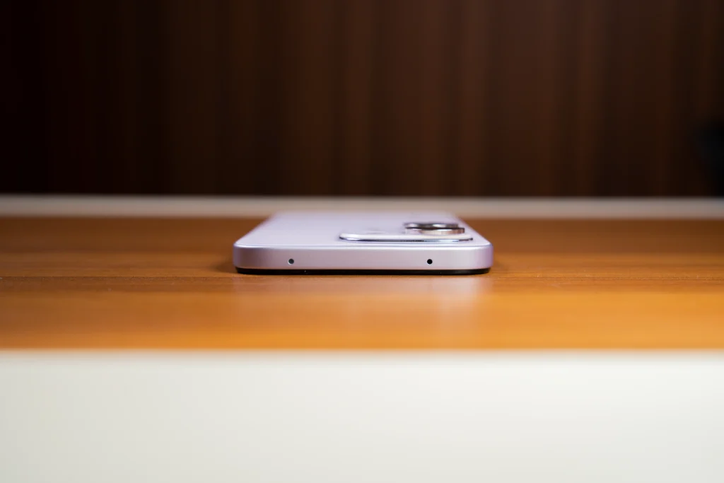 A low-angle profile shot showing the top edge of the purple HONOR 600S 5G resting flat on a wooden table.