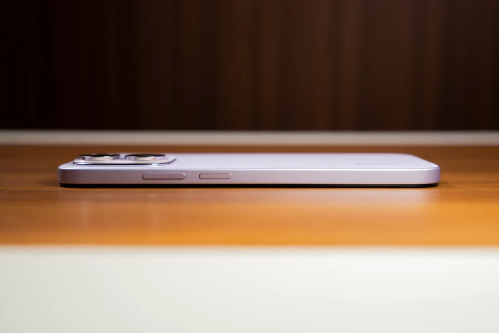 A side profile view showing the volume rocker and power button on the purple HONOR 600S 5G lying on a wooden surface.